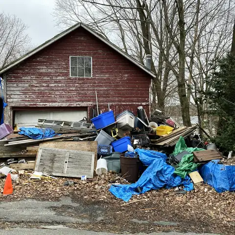 A pile of debris in front of a red barn