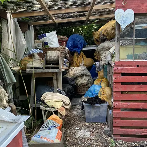 A shed porch piled with bags, boxes and old household items